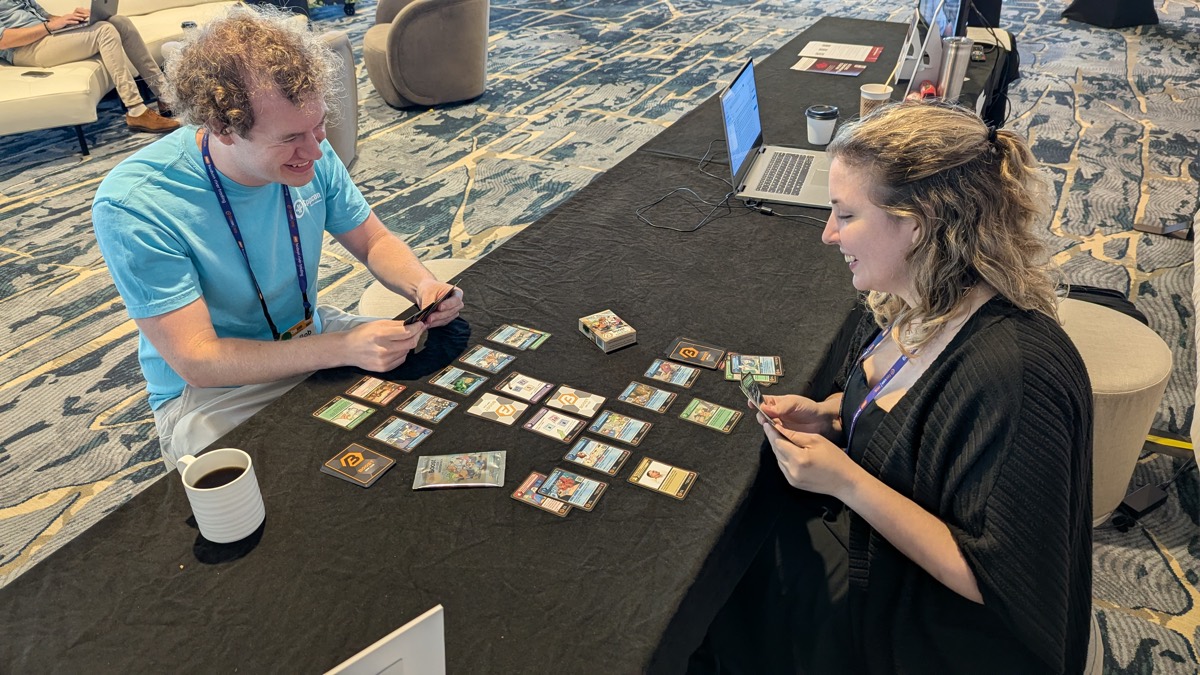 Two attendees playing Boost CCG at the Boost Lounge table during CppCon 2026.